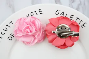Detail of pink and coral fabric flower brooches showing dual clip and pin backing