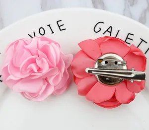 Dual-purpose fabric rose flower brooch and hair clip with pink satin petals on ceramic plate