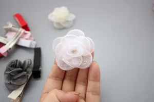 Detail van witte meerlaagse mesh roos broche in de hand met diverse kleurkeuzes