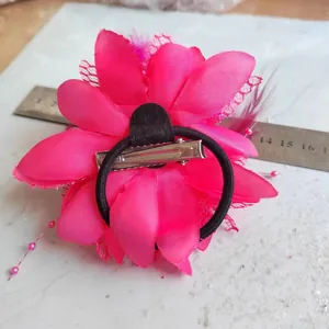 Macro view of magenta feather flower hair clip with dual metal clip and elastic band