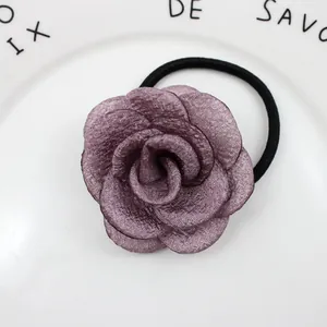 Nahaufnahme des tiefvioletten Stoff-Rosen-Haargummis auf einem weißen Keramiktablett