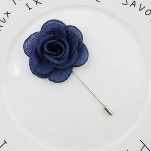 Detailed close-up of dark blue fabric rose lapel pin with textured petals on ceramic plate