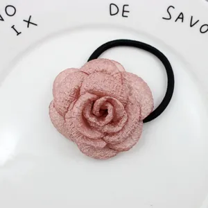 Makro-Detail eines weichen Haargummis mit rosa Stoff-Kamelienblüte für Damen und Mädchen