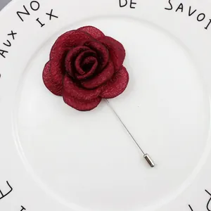 Macro detail of dark red fabric rose brooch with silver long pin for suits and dresses