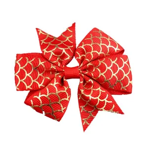 Close-up of red grosgrain hair bow with golden fish scale pattern and textured detail