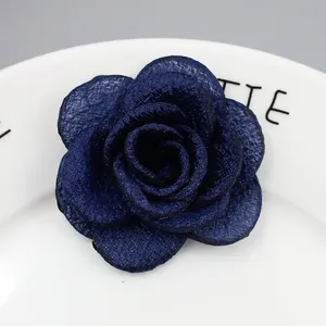 Detailopname van een marineblauwe stoffen camelia broche op een keramisch bord