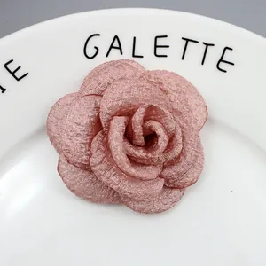 Macro-opname van handgemaakte camelia-broche in oudroze stof met organza laagjes