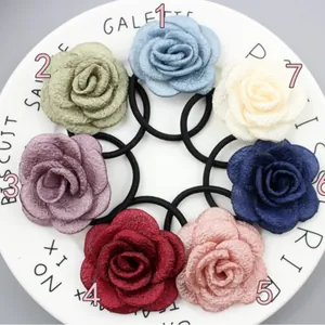 Set aus sieben floralen Stoff-Haargummis in verschiedenen Farben auf einem Teller.