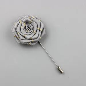 Detailed view of grey fabric rose lapel pin with gold texture and long silver needle