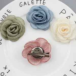 Franse stijl stoffen camelia broches in vier kleuren op een wit keramisch bord