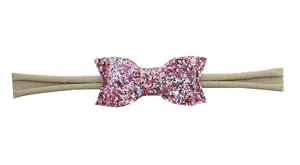 Détail d'un nœud à paillettes roses et bandeau en nylon élastique kaki pour bébés