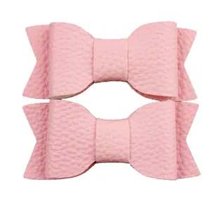 Detail of two pink faux leather hair bows featuring a soft lychee grain texture for girls