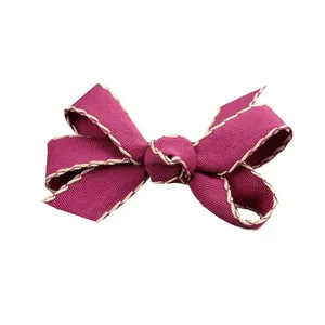 Detailaufnahme einer dunkelpurpurnen Ripsbandschleife mit beigen Nähten für DIY-Haarschmuck