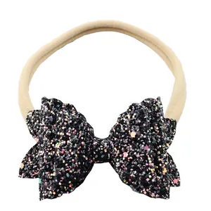 Detailopname van de zwarte glitterstrik op een huidkleurige elastische baby-haarband