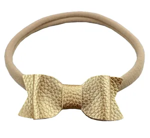 Detail of high-elastic nylon headband and textured golden faux leather bow for infants