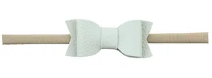 Close-up of soft white faux leather bow with lychee texture on elastic nylon baby headband