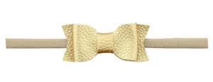 Detailed view of golden faux leather bow with litchi texture on elastic nylon baby headband