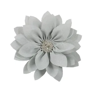 Detailed view of grey ruffled fabric flower hair clip with sparkling rhinestone center