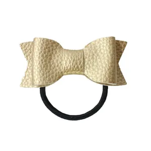 Detailed view of the gold lychee texture leather bow on a black elastic hair tie