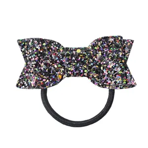 Détail d'un élastique pour fille avec paillettes noires et un grand nœud brillant