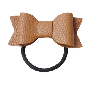 Detailed close-up of brown faux leather bow hair tie with pebble grain texture
