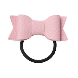 Detail of pink faux leather bow hair tie with textured finish on white background