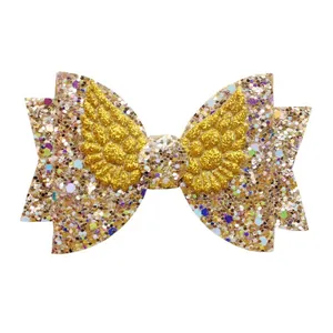 Close-up of golden glitter bow hair accessory with 3D angel wings and sequins