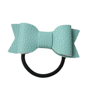 Detail of mint green lychee textured faux leather bow on a black elastic hair tie