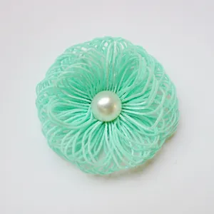 Detail of mint green woven fabric flower accessory with central faux pearl bead