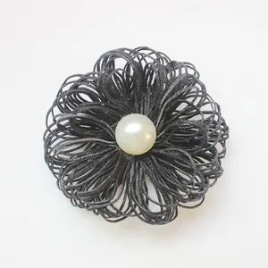 Detail van de handgemaakte zwarte gelaagde bloemspeld met een vintage witte parel in het midden