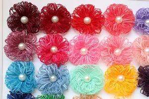 Detailed view of handmade fabric flower accessories with center pearl in multiple colors