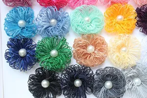 Close-up of handmade fabric flower accessories with centered pearl in various colors