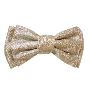 Close-up of glitter bow hair clip with colorful laser sequins on champagne gold fabric