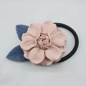 Détail d'un camélia en tissu rose avec feuilles bleues sur un élastique noir