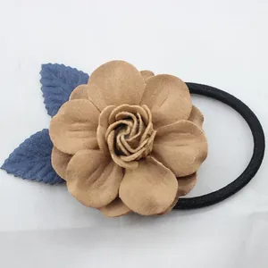 Détail d'élastique à cheveux avec fleur marron 3D et feuilles bleues sur tissu blanc