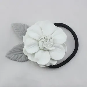 Détail d'un chouchou à fleurs avec pétales blancs, feuilles grises et élastique noir
