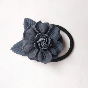 Détail d'un chouchou camélia bleu marine avec feuilles vertes sur une surface blanche