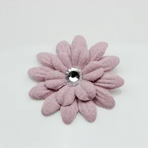 Dettaglio di un fiore in tessuto rosa pallido con petali multistrato e centro in cristallo