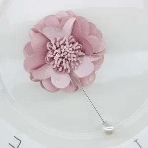 Detail of dusty pink fabric flower brooch with silver pin and white pearl end