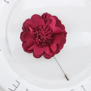 Detailed close-up of a handmade burgundy satin flower brooch with a silver stick pin