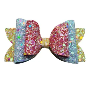 Close-up of triple-layered sequin bow accessory in gold, light blue, and pink glitter fabric