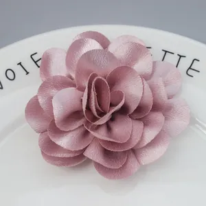 Detailed macro view of handmade light pink chiffon satin flower accessory on a white plate