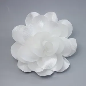 Detailed close-up of handmade white chiffon 3D floral ornament with layered petals