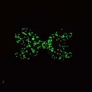 Detailed view of glow-in-the-dark hair clip with green fluorescent bow pattern