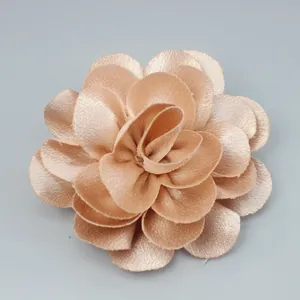 Macro detail of champagne satin handmade flower accessory with layered glossy petals