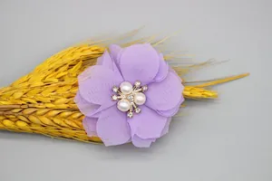 Close-up of purple chiffon flower with central pearls and rhinestones on grey background