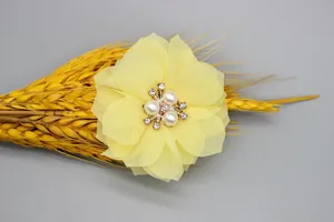 Macro detail of handmade chiffon flower with pearls and rhinestones on wheat background