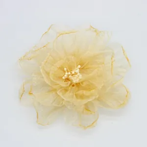Vista macro del fermaglio a fiore in organza con petali color oro champagne e stami bianchi
