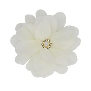 Detailed view of a white chiffon flower hair clip with pearl and rhinestone center decoration