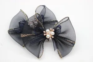 Dettaglio fiocco in organza nera con bordo dorato e grappolo di perle e strass